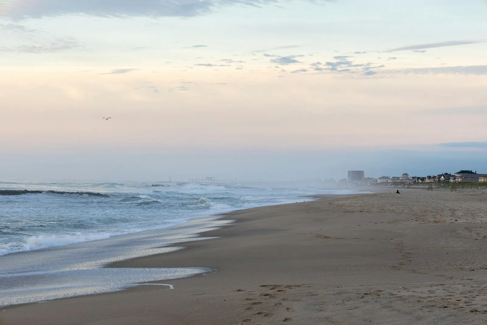 A quiet Jersey Shore beach at dawn, waves rolling in near shore houses